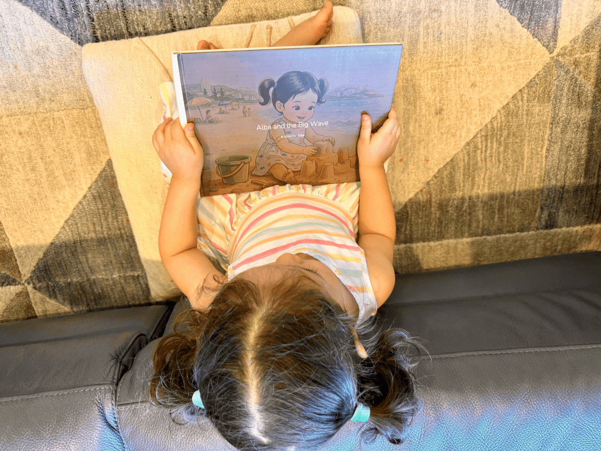 An Almia personalised children's hardcover book on a cream surface, the cover showing the child as the illustrated hero of the story.